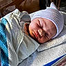 newborn, baby, sleeping, infant, face, portrait, striped_hat, blanket, swaddled, hospital, bassinette, indoors, soft_lighting, peaceful, resting, closed_eyes, cozy, textile, headwear, photography