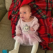 Penelope is registered to the contest to win money with this photo: baby, infant, child, pink_dress, cat_design, blanket, red_plaid, couch, pacifier, white_tights, sitting, indoors, portrait, cute, cozy, comfort, young_child, smiling, face, clothing