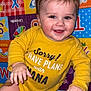 baby, child, smiling, yellow_onesie, band_aid, playmat, colorful, alphabet, happy, face, indoors, cute, infant, person, skin, hand, leg, baby_clothing, lying_down, expression