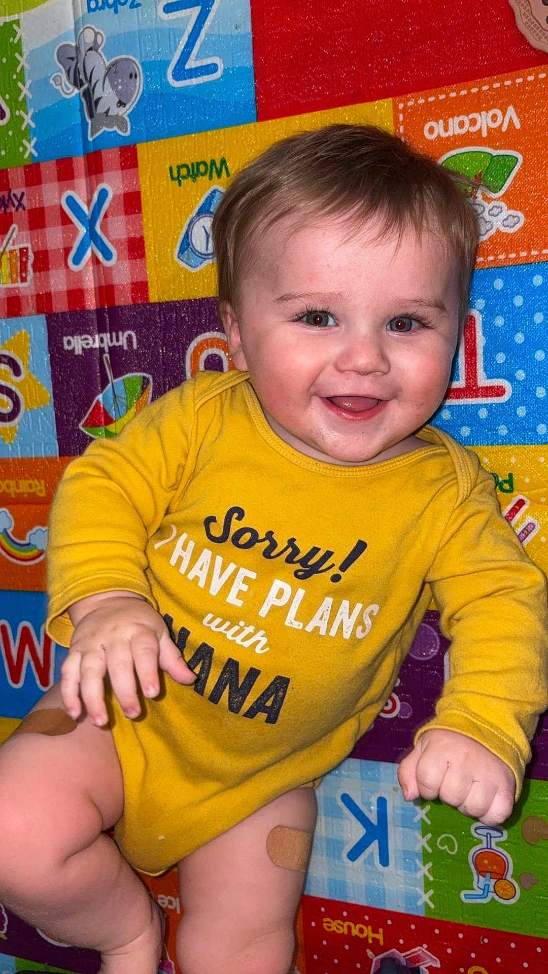 Hayston joined the competition — help win amazing prizes! baby, child, smiling, yellow_onesie, band_aid, playmat, colorful, alphabet, happy, face, indoors, cute, infant, person, skin, hand, leg, baby_clothing, lying_down, expression