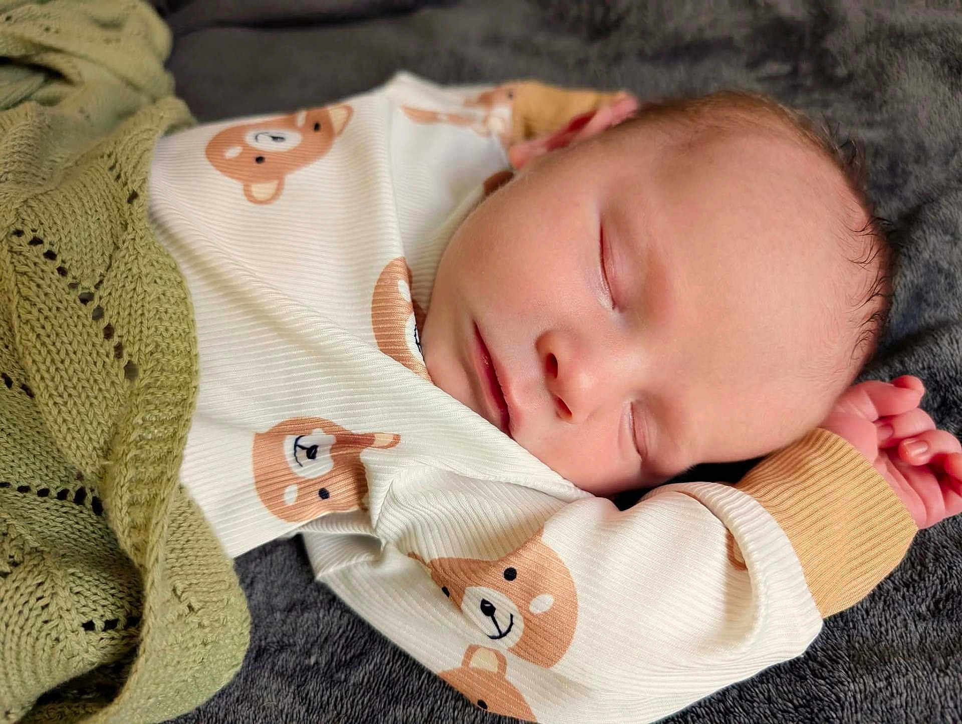Leon is registered to the contest to win money with this photo: baby, sleeping, onesie, bear_print, blanket, knitted, cozy, infant, peaceful, soft, face, hand, cute, resting, child, portrait, newborn, warm, comfort, sleep
