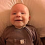 Leon is registered to the contest to win money with this photo: baby, smile, infant, clothing, brown_outfit, cushion, portrait, face, happy, child, indoors, soft_lighting, closeup, cute, cozy, ribbed_fabric, baby_garment, small_child, comfortable, relaxed