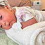 Anaiah is registered to the contest to win money with this photo: baby, infant, towel, blanket, mittens, onesie, floral_pattern, lying_down, cozy, soft_texture, indoor, newborn, face, cute, child, skin, head, sleepwear, resting, warm_light