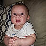 Wyatt is registered to the contest to win money with this photo: baby, child, infant, face, hands, couch, cushion, clothing, onesie, pattern, indoor, portrait, cute, curious, seated, chubby, skin, head, eyes, expression