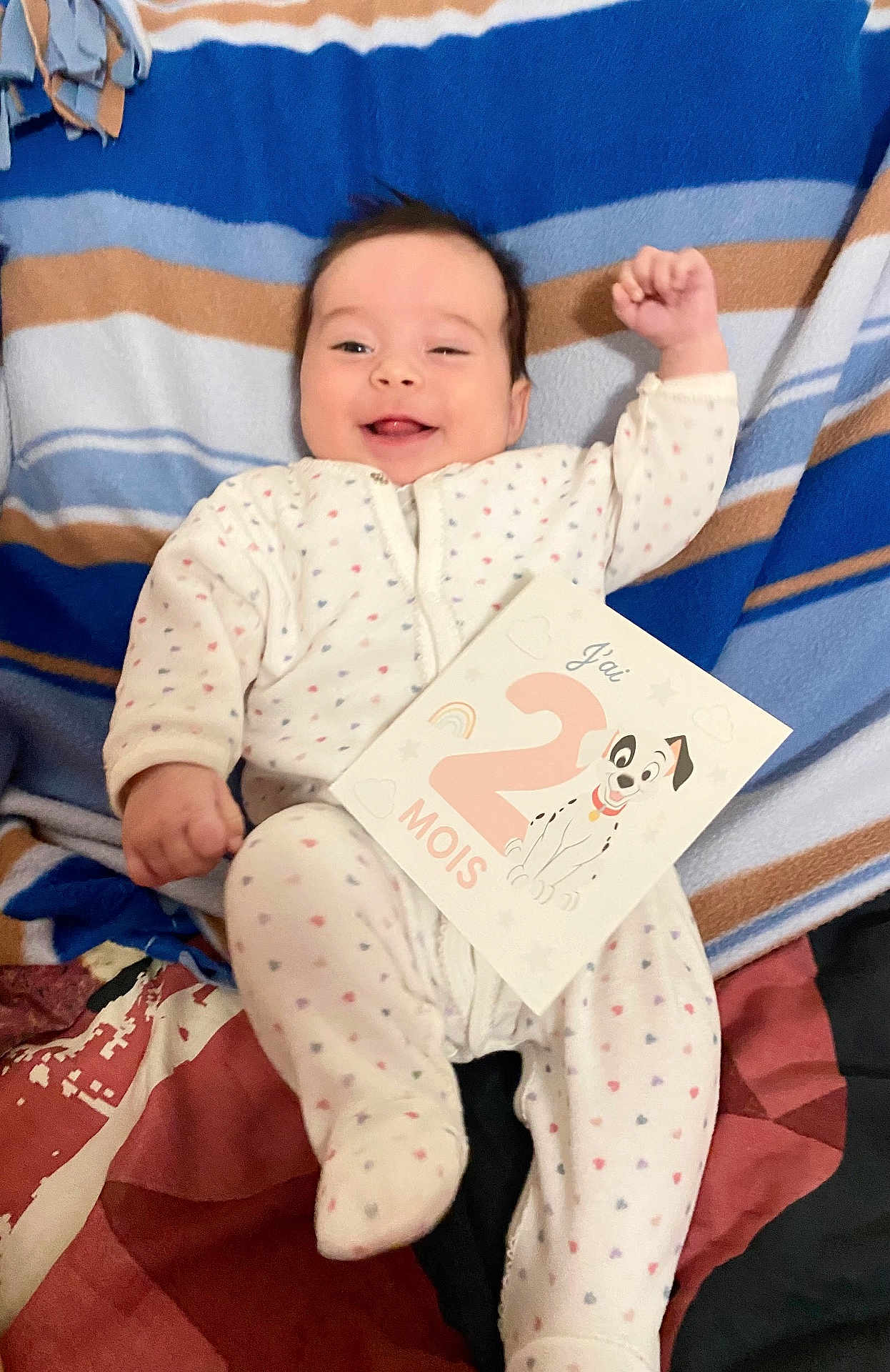Mattea a rejoint le concours — aidez-le/la à gagner de superbes lots ! baby, infant, smiling, onesie, blanket, card, celebration, polka_dots, lying_down, face, happy, cute, child, portrait, indoors, colorful, striped_blanket, raised_arm, two_months, illustration