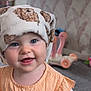 Aria is registered to the contest to win money with this photo: baby, child, smiling, face, blue_eyes, towel, headwear, orange_dress, indoor, toy, carpet, wallpaper, person, cute, happy, infant, portrait, closeup, childhood, home