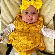 Jade a rejoint le concours — aidez-le/la à gagner de superbes lots ! baby, infant, headband, yellow_bow, yellow_dress, smile, face, eyes, cheeks, blanket, onesie, heart_pattern, sleeves, lying_down, buckle_strap, textile_texture, portrait, indoors, cute, happy