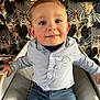 Lyam a rejoint le concours — aidez-le/la à gagner de superbes lots ! child, toddler, boy, face, eyes, smile, shirt, jeans, chair, seated, ear, cheek, closeup, portrait, family_photo, patterned_wallpaper, indoor, home_interior, short_hair, baby_chair