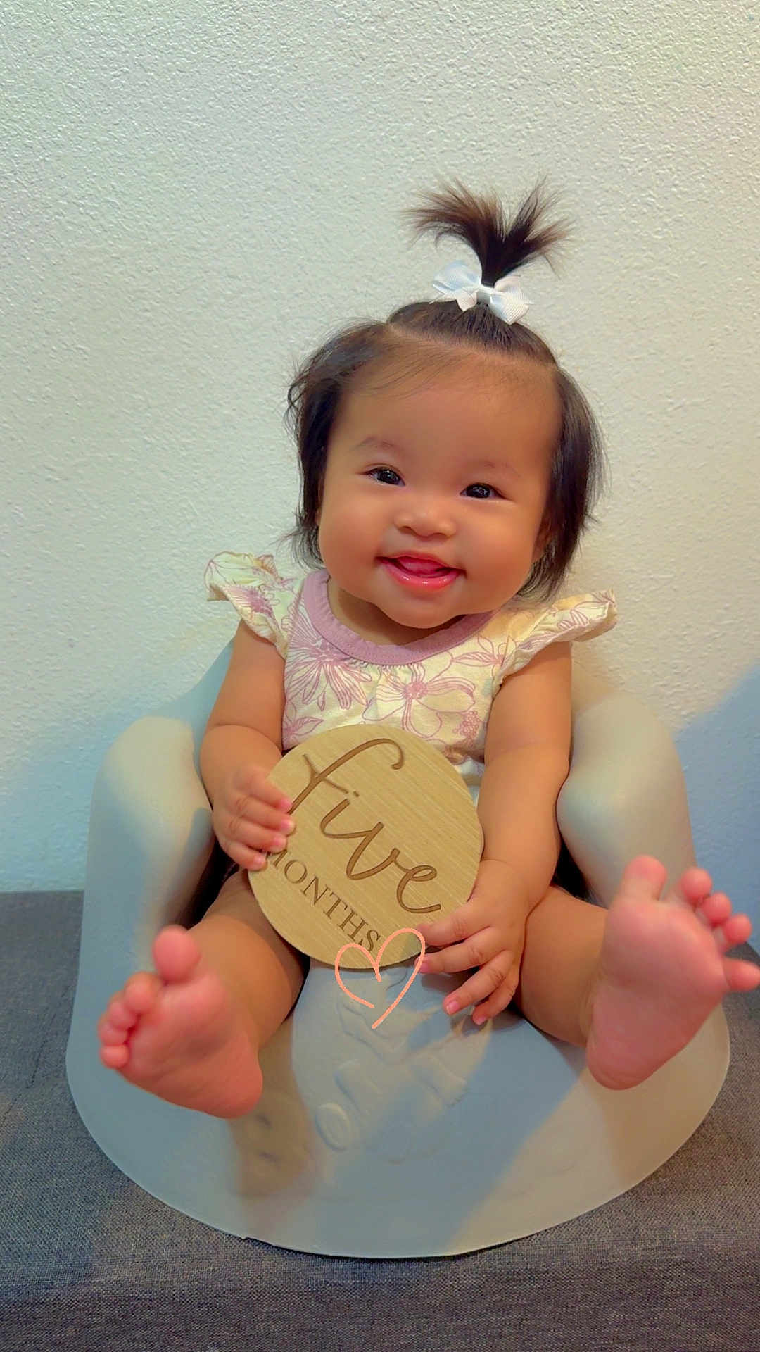 Nevaeh Jade is registered to the contest to win money with this photo: baby, child, smiling, happy, infant, sitting, baby_seat, wooden_sign, five_months, hair_bow, cute, feet, hands, portrait, indoor, wall, clothing, person, young_child, expression