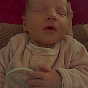 Isaé participe au concours pour gagner de l'argent avec cette photo : baby, newborn, sleeping, infant, pink_clothing, hand, face, closed_eyes, soft_fabric, floral_pattern, comfort, resting, portrait, cute, cozy, indoor, child, person, warm, peaceful