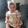 baby, child, girl, smiling, headband, bow, dress, bracelet, socks, lace, couch, cushions, indoor, portrait, sitting, cute, happy, infant, person, furniture