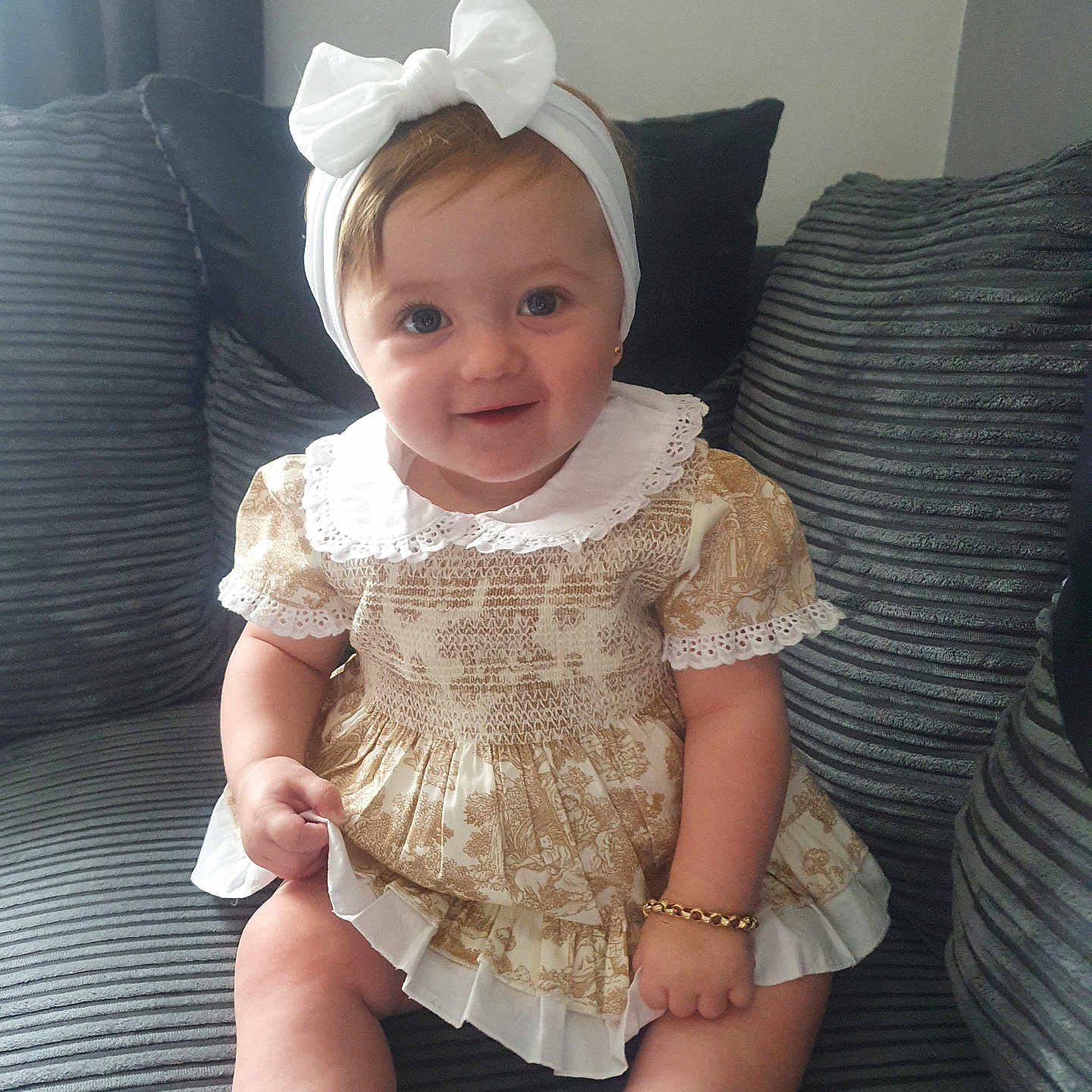 Valencia-Maria is registered to the contest to win money with this photo: baby, bow, bracelet, child, couch, cushions, cute, dress, furniture, girl, happy, headband, indoor, infant, lace, person, portrait, sitting, smiling, socks