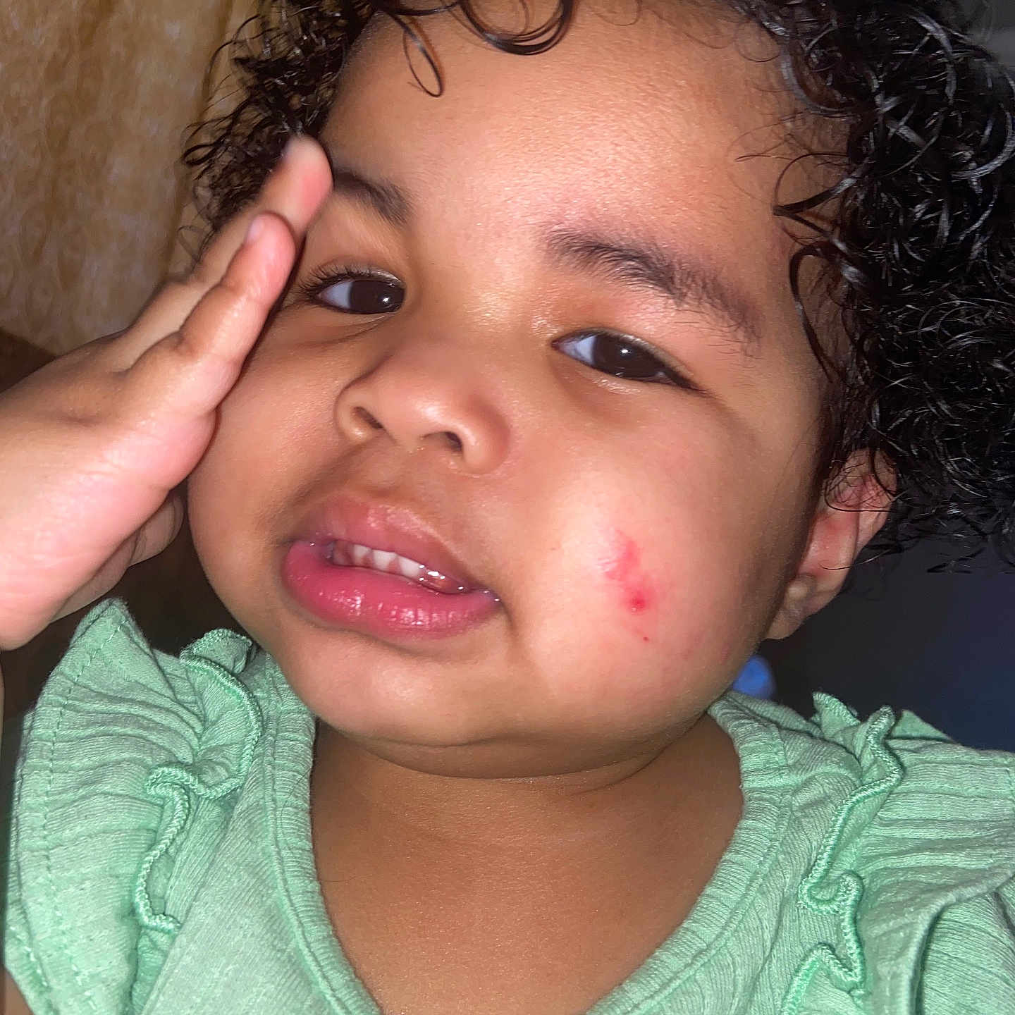Triana is registered to the contest to win money with this photo: baby_skin, cheek, child, closeup, curly_hair, cute, expression, face, flash, green_clothing, hand, human, indoor, person, portrait, red_mark, ruffled_clothing, smile, toddler, young_child