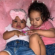 Triana is registered to the contest to win money with this photo: baby, blanket, casual_clothing, child, close_up, cuddling, cute, denim_shorts, face, hands, indoor, infant, pink_bow, pink_shirt, portrait, skin, sleepy, soft_texture, toddler, two_children