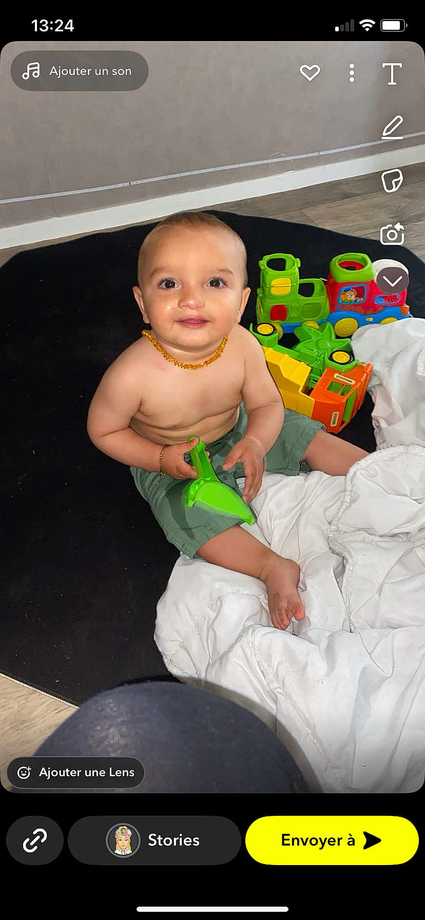Damon participe au concours pour gagner de l'argent avec cette photo : baby, child, toy, green_toy, colorful_toys, blanket, carpet, floor, indoor, smiling, happy, sitting, shorts, bracelet, necklace, cute, playtime, infant, person, portrait