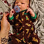 Chase joined the competition — help win amazing prizes! baby, pacifier, onesie, brown, moose_pattern, infant, bed, blanket, hand, tattoo, crown_tattoo, heart_tattoo, person, sleepwear, newborn, clothing, pattern, cute, lying_down, indoor