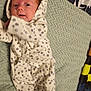 Avacyn is registered to the contest to win money with this photo: baby, infant, onesie, blanket, patterned_clothing, cute, newborn, lying_down, soft_texture, fabric, cozy, child, small, face, person, sleepwear, indoor, curious, hooded_clothing, resting