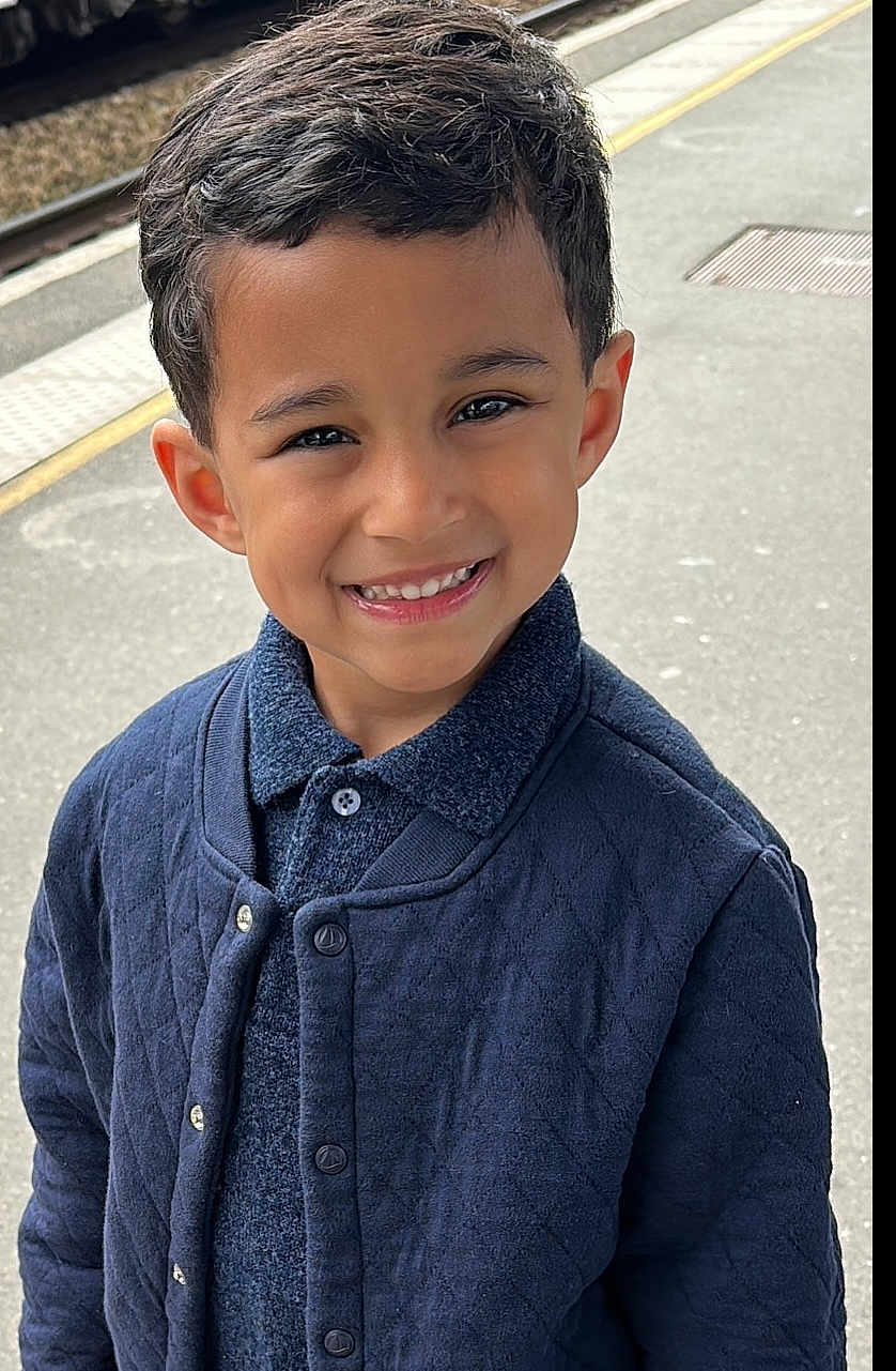 Zayn participe au concours pour gagner de l'argent avec cette photo : child, boy, smiling, face, portrait, young, clothing, jacket, outdoor, train_platform, urban, casual, happy, person, standing, cute, fashion, hair, skin, eyes