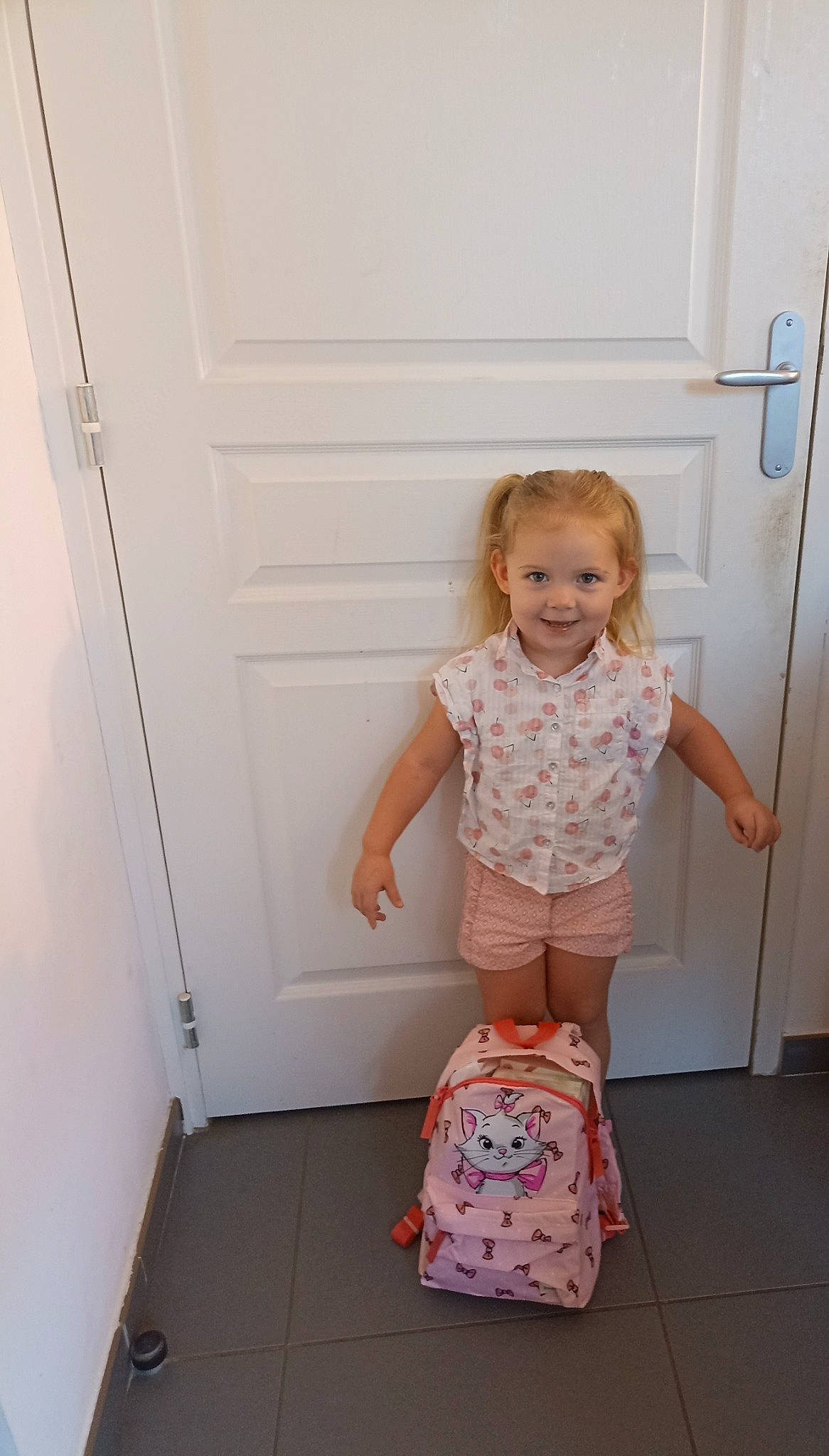 Tyana participe au concours pour gagner de l'argent avec cette photo : baby_toddler_clothing, child, cleanliness, door, floor, flooring, fun, human_leg, joy, knee, magenta, pattern, person, pink, shorts, shoulder, sleeve, smile, t_shirt, toddler