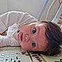 baby, blue_eyes, child, curious, face, hair, indoor, laying_down, mat, patterned, play_mat, portrait, rumpled_clothing, sideways, toddler, white_clothing, young_child, expression, close_up, floor