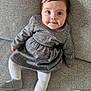 Ely a rejoint le concours — aidez-le/la à gagner de superbes lots ! baby, child, girl, plaid_dress, pink_hair_clip, white_tights, gray_shoes, couch, gray_fabric, soft_cloth, sitting, smiling, blue_eyes, curly_hair, indoor, portrait, cute, cozy, comfortable, infant