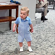 Billie is registered to the contest to win money with this photo: adult, baby, clothing, face, footwear, furniture, head, jeans, male, man, pants, person, photography, portrait, shoe, shorts, sitting, sleeve, standing, table