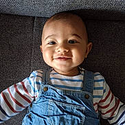 Arthur a rejoint le concours — aidez-le/la à gagner de superbes lots ! baby, child, smiling, denim_overalls, striped_shirt, couch, indoor, portrait, happy, infant, face, person, clothing, seated, cute, young, one_child, head, skin, eyes