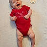 baby, laughing, red_onesie, infant, celebration, blanket, smile, portrait, cute, child, skin, happy, lying_down, plaque, holiday, fourth_of_july, indoors, person, newborn, soft_texture