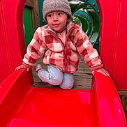 Agathe participe au concours pour gagner de l'argent avec cette photo : child, slide, playground, red, jacket, hat, tunnel, wood, outdoor, play, curious, clothing, person, fun, casual, winter, park, active, smiling, kneeling