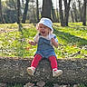 baby, bokeh, bucket_hat, child, daisies, denim_overalls, forest, grass, joyful_expression, laughing, log, nature, outdoor, portrait, red_tights, sitting, sunlight, toddler, trees, white_shoes