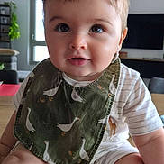 Noé a rejoint le concours — aidez-le/la à gagner de superbes lots ! baby, child, infant, bib, table, indoor, home, curious, smile, face, eyes, clothing, legs, sitting, wood, furniture, window, plant, television, casual