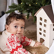 Riad joined the competition — help win amazing prizes! baby, child, christmas_lights, christmas_tree, crawling, curly_hair, cute, decor, festive, fur_rug, holiday, holiday_season, indoor, miniature_house, portrait, red_pattern, soft_lighting, sweater, warm, white_sweater