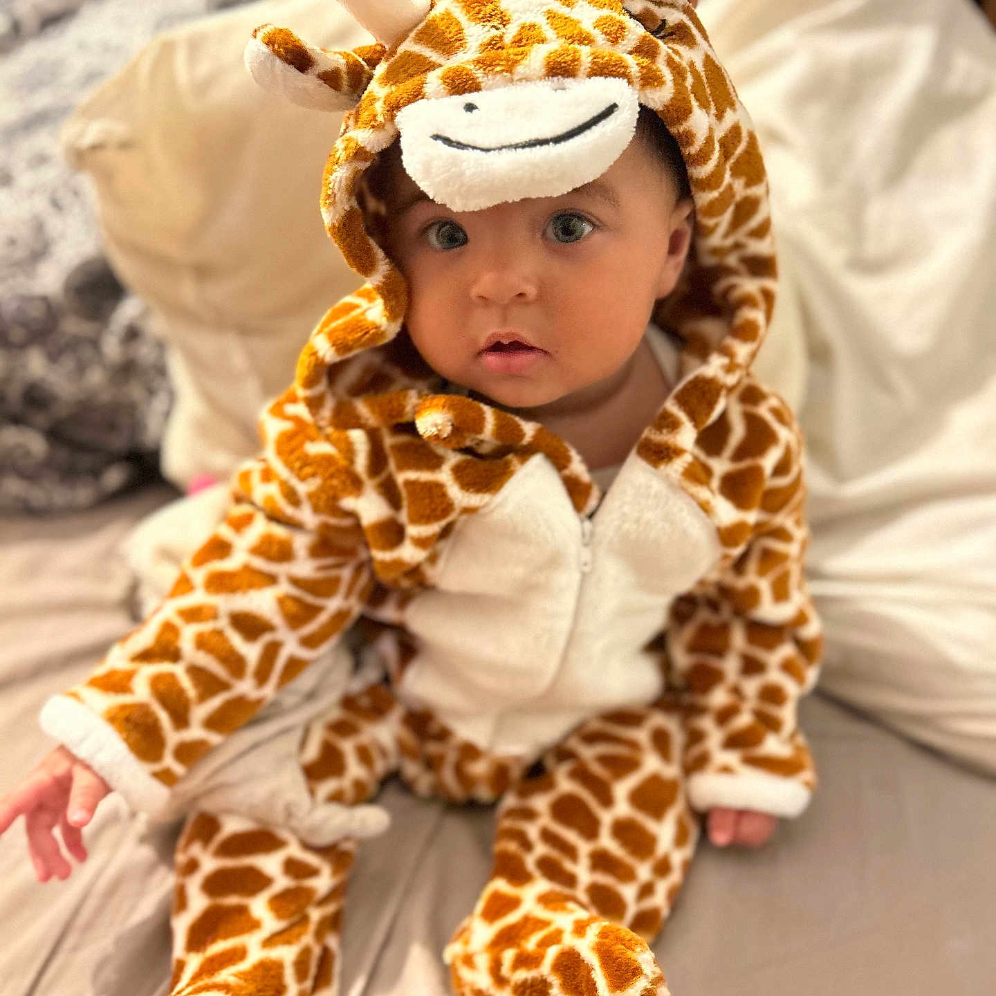 Norah a rejoint le concours — aidez-le/la à gagner de superbes lots ! adorable, animal_print, baby, bed, blanket, child, childrens_clothing, cozy, cute, giraffe_costume, indoor, infant, looking_at_camera, onesie, pillow, plush, portrait, sitting, soft_toy_style, warm