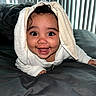 Alani joined the competition — help win amazing prizes! baby, child, smiling, happy, towel, bed, blanket, indoor, face, crawling, person, head, curly_hair, cute, infant, white_clothing, playful, expression, closeup, home