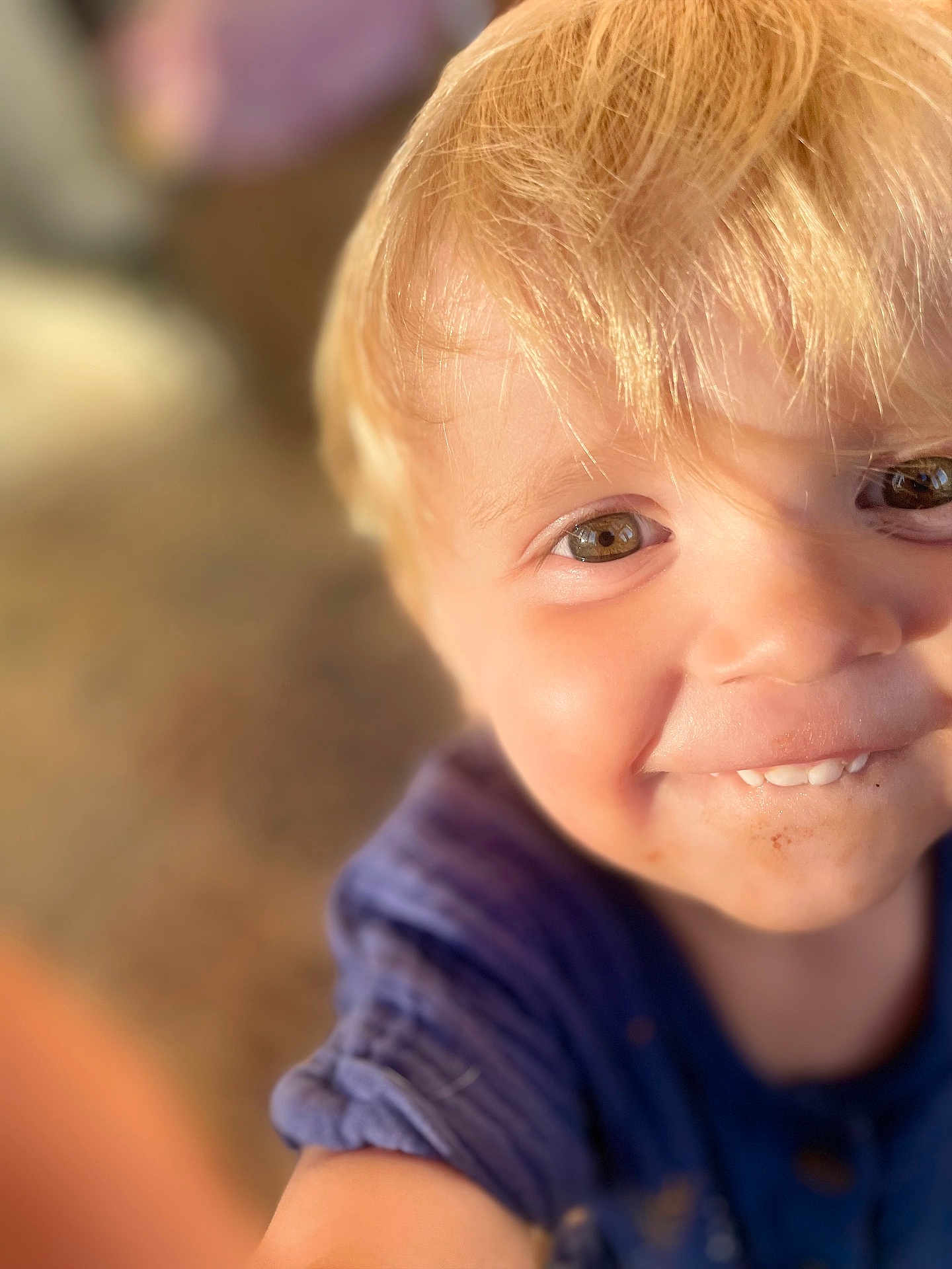 Leythen participe au concours pour gagner de l'argent avec cette photo : child, toddler, smiling, blonde_hair, face, eyes, close_up, portrait, natural_light, curious, happy, casual_clothing, messy_face, skin, person, young_child, cute, indoors, warm_tone, soft_focus