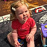 Chloe is registered to the contest to win money with this photo: baby, child, girl, red_onesie, bows, remote_control, toy, blanket, carpet, indoor, cute, smiling, sitting, chubby_cheeks, playtime, infant, home, person, expression, polka_dot