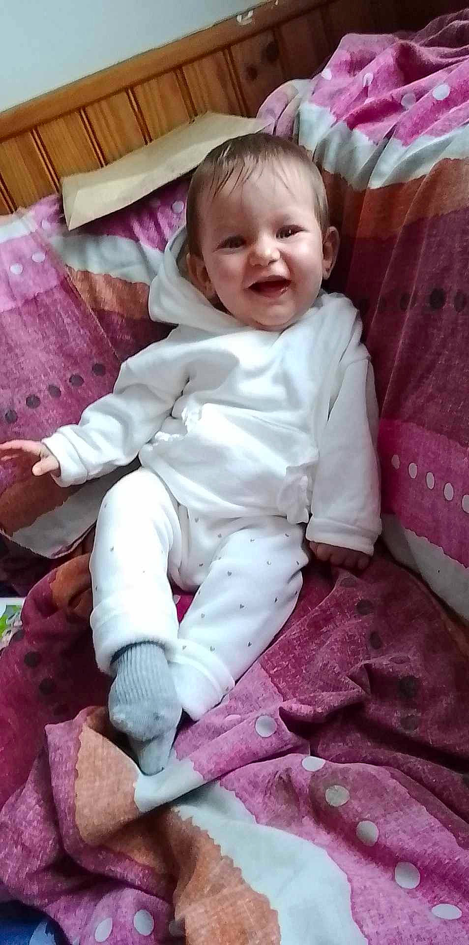 Layanah participe au concours pour gagner de l'argent avec cette photo : baby, baby_toddler_clothing, cheek, child, comfort, foot, head, human_leg, lap, linens, magenta, person, pink, purple, sitting, skin, sleeve, smile, sock, thigh