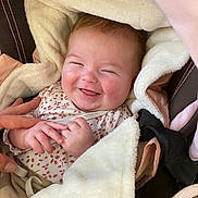 Athéna participe au concours pour gagner de l'argent avec cette photo : baby, smiling, blanket, cozy, cute, infant, hand, person, clothing, fabric, pink, brown, soft, happy, face, closeup, indoors, seat, carseat, cute_expression