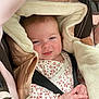 Athéna participe au concours pour gagner de l'argent avec cette photo : baby, infant, car_seat, hooded_jacket, fluffy, clothing, face, hands, expression, cute, child, person, seatbelt, pink, white, patterned_clothing, warm, indoor, portrait, smile