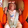 baby, infant, car_seat, orange, pink_clothing, headband, pacifier, sleeping, child, straps, safety, cute, newborn, resting, soft, padded, indoors, peaceful, seatbelt, transport