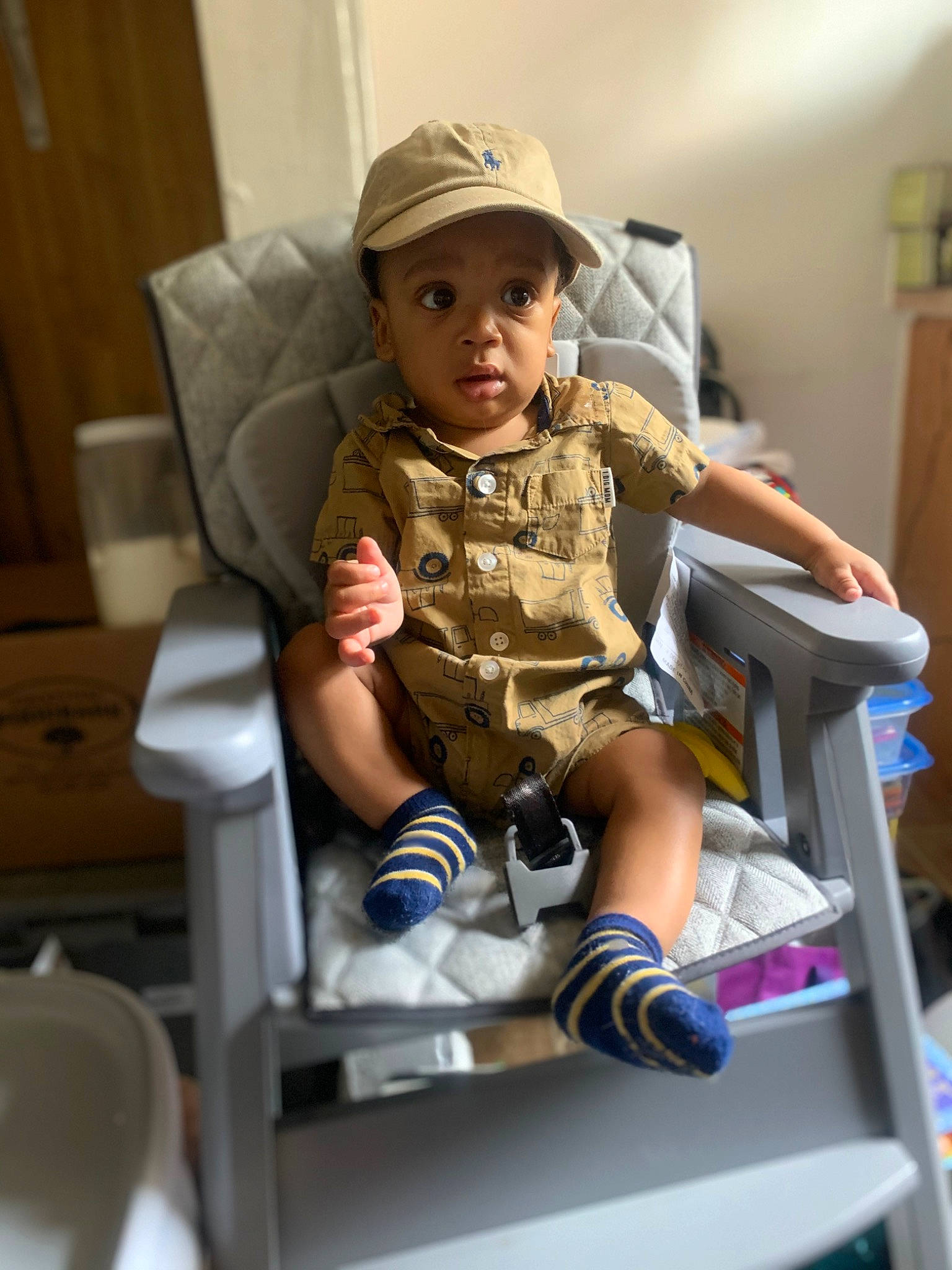 Augustus is registered to the contest to win money with this photo: baby, baby_products, baby_safety, baby_toddler_clothing, baseball_cap, cap, child, comfort, fun, headwear, human_leg, knee, leg, leisure, person, room, shorts, sitting, sleeve, sneakers