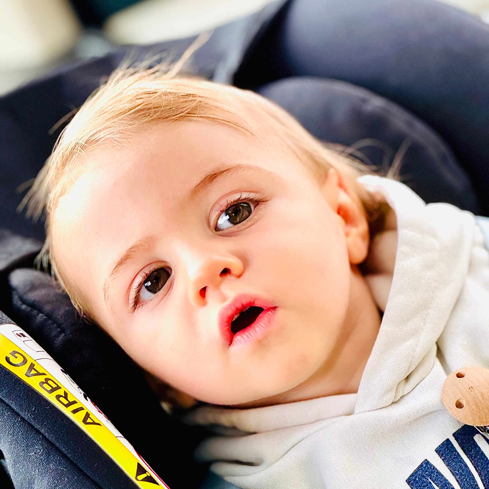 Orphee a rejoint le concours — aidez-le/la à gagner de superbes lots ! airbag_label, baby, car_seat, casual_clothing, child, close_up, curious, expression, eyes, face, head, hoodie, indoor, infant, portrait, safety, seat, seatbelt, toddler, young_child