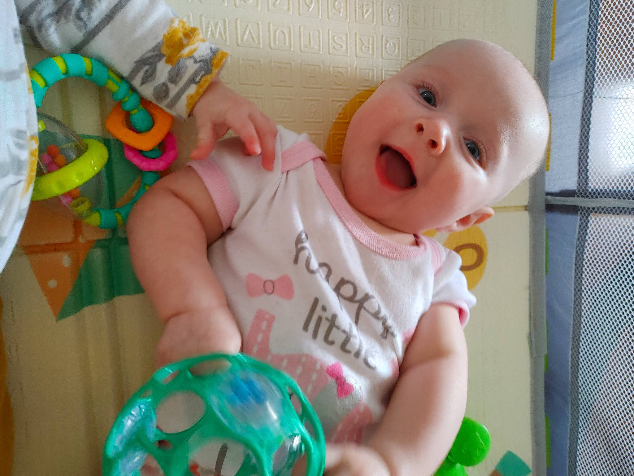 Lillian is registered to the contest to win money with this photo: arm, baby, baby_playing_with_toys, baby_safety, baby_toddler_clothing, cheek, child, cradle, finger, fun, green, happy, head, human_body, infant_bed, nose, person, product, skin, toddler