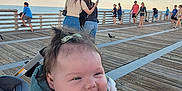 Analina joined the competition — help win amazing prizes! baby, smiling, child, pier, ocean, sky, people, wooden_boardwalk, casual_clothing, woman, holding, outdoor, daylight, happy, infant, person, nature, blue_sky, water, crowd
