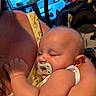 baby, sleeping, pacifier, arm, person, yellow_dress, floral_pattern, indoor, window, car, blue_sky, child, closeup, peaceful, infant, holding, parent, resting, soft_light, cute