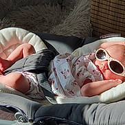 Luna a rejoint le concours — aidez-le/la à gagner de superbes lots ! baby, sunglasses, baby_seat, infant, sunlight, relaxing, cushion, clothing, footwear, indoor, comfort, cute, person, headwear, fashion, resting, skin, small_person, seat_belt, accessory