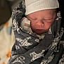 newborn, baby, sleeping, hat, blanket, swaddled, face, infant, cozy, soft_lighting, peaceful, closeup, cute, patterned_blanket, indoors, portrait, headwear, child, resting, warm