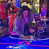 arcade, air_hockey, child, woman, neon_lights, game, fun, indoor, people, playing, family, smile, crowd, entertainment, arcade_machine, colorful, leisure, hockey_puck, happy, interaction