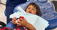 Francisco Zayden is registered to the contest to win money with this photo: child, dentist_chair, toy_car, dental_assistant, medical_setting, blue_chair, red_clothing, dinosaur_print, plastic_cover, gloves, computer_monitor, countertop, cabinet, floor_tiles, waiting, patient, healthcare, clinic, young_child, casual