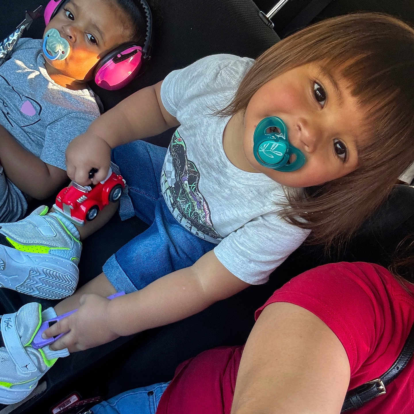 Francisco Zayden is registered to the contest to win money with this photo: child, toddler, pacifier, headphones, toy_car, car_seat, sneakers, clothing, person, indoor, seatbelt, hair, cute, smile, playful, sunlight, window, seat, casual, baby